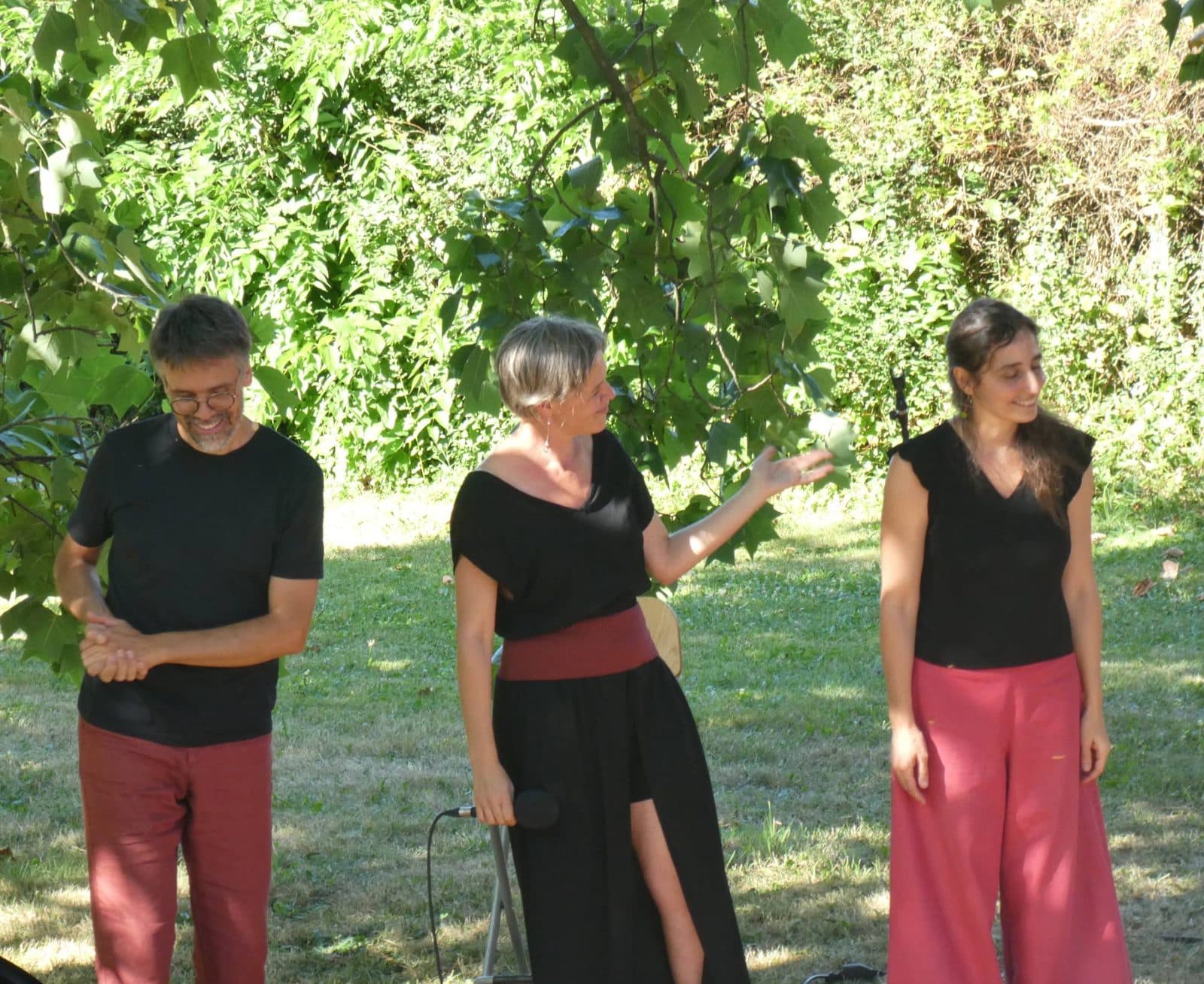 Les trois artistes du Trio Volubile saluent le public dans l’herbe, sous les arbres