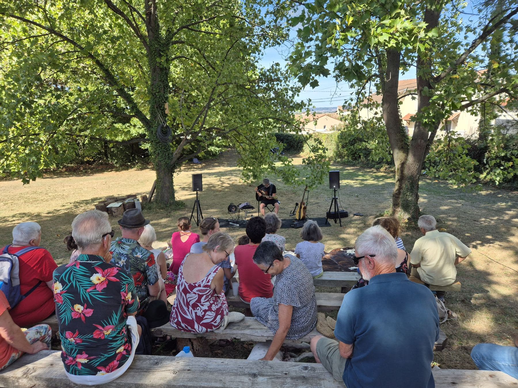 Vue depuis l’arrière du public : le musicien seul entre ses enceintes, et les toits du village au loin