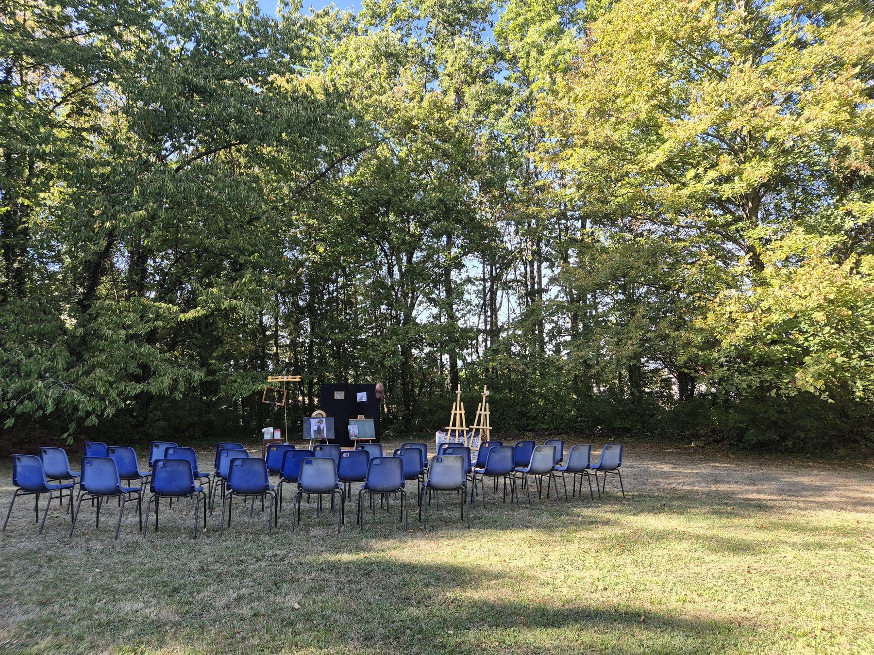 Les chaises bleues disposées en arc de cercle dans l’herbe, face au décor de la conférence